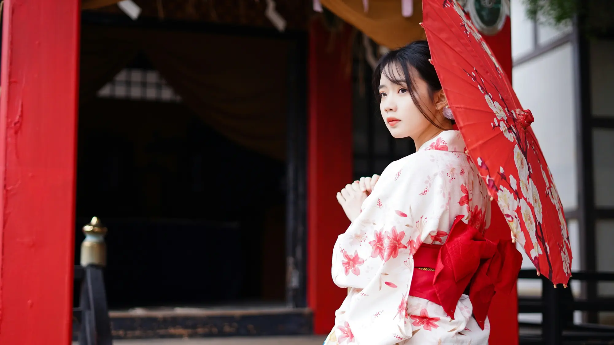 Woman in a floral kimono with a red wagasa parasol at a shrine